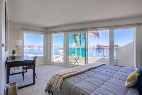 a bedroom with a bed and a desk and windows at Jamaica Sands in San Diego