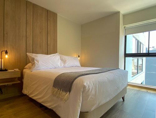 a bedroom with a bed with white sheets and a window at Pod by Wynwood House in Lima