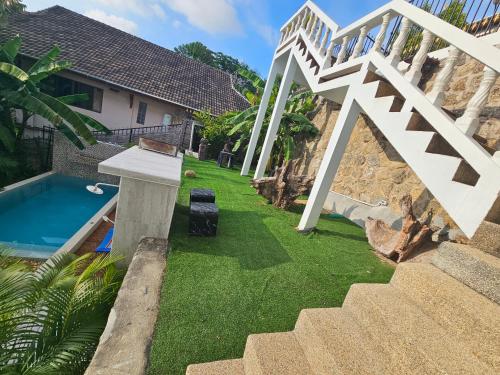 a backyard with a swimming pool and a white stairway at Castle Villa Phuket in Kamala Beach