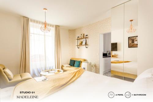 ein weißes Schlafzimmer mit einem großen Bett und einem Stuhl in der Unterkunft Beauquartier - Madeleine in Paris