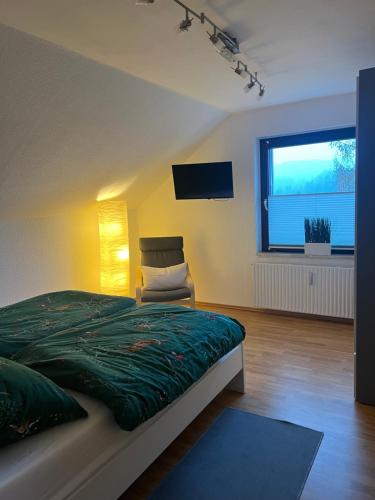 a bedroom with a bed and a chair and a television at Ferienwohnung Nannerl in Bad Sachsa