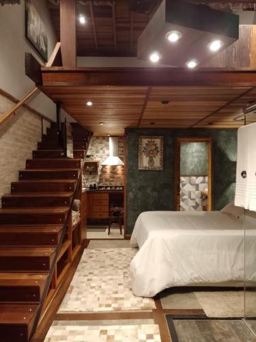 - une chambre avec un escalier et un lit avec un couvre-lit dans l'établissement CHALÉS LUAR DO PICO, à Santo Antônio do Pinhal