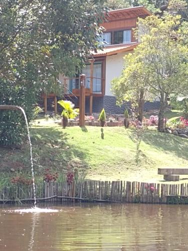 a house with a fountain in front of a body of water at CHALÉS LUAR DO PICO in Santo Antônio do Pinhal