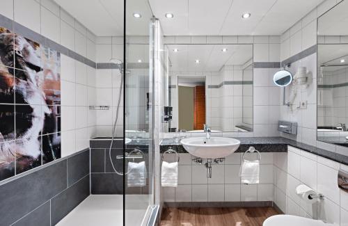 a bathroom with a sink and a shower at Leonardo Hotel Esslingen in Esslingen