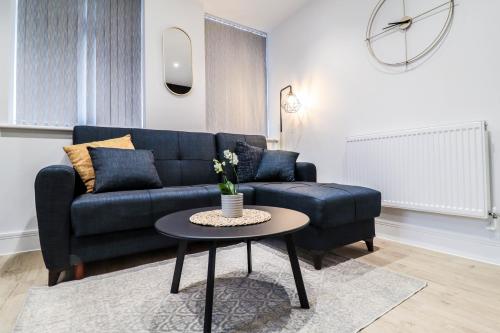 a living room with a blue couch and a table at London Luxury Apartments in High Wycombe in Buckinghamshire