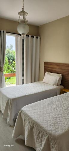 Pousada do Lago 2 في بتروبوليس: سريرين في غرفة نوم مع نافذة