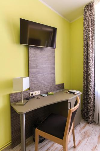 a desk with a monitor on a yellow wall at Restaurant & Pension Eshramo in Barth