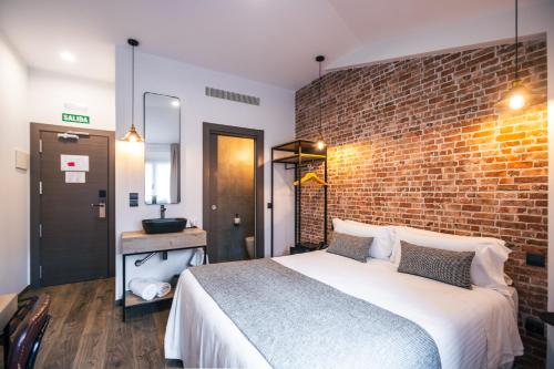 a bedroom with a large bed and a brick wall at Le Petit Boutique Hotel in Santander