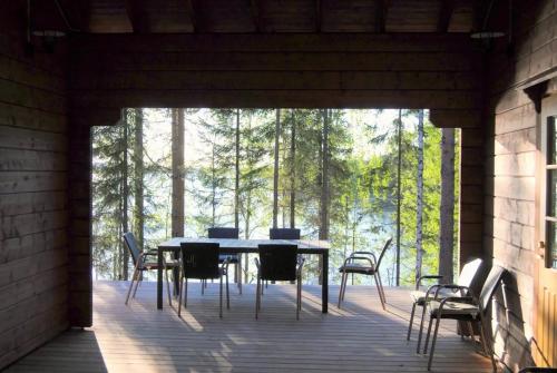 une table et des chaises sur une terrasse avec vue sur les arbres dans l'établissement Beautiful and spacious lakeside cottages, à Imatra
