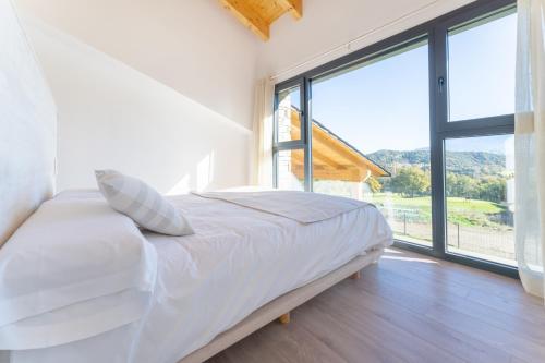 a bedroom with a white bed with a large window at Casa rural de lujo en Alt Urgell, Pirineos. in Aravell