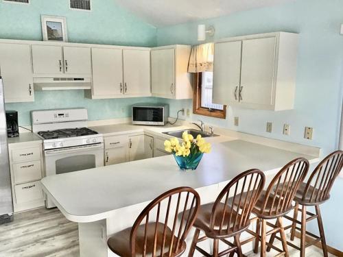 una cocina con armarios blancos y una mesa con sillas. en Vacation Rental With Pool On Lbi, en Brant Beach