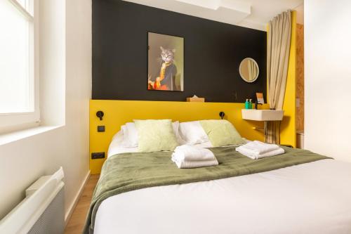 1 dormitorio con 1 cama grande y cabecero amarillo en Le Chat Qui Dort - Vieux Lille II, en Lille