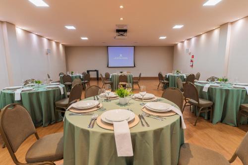 a conference room with tables and chairs and a screen at Ucayali Hotel in Sinop