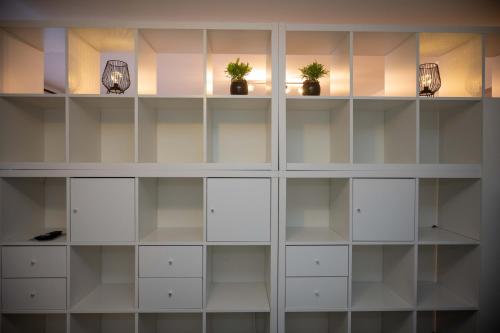 a room with white shelves with potted plants on them at Studio apartman Daruvar in Daruvar