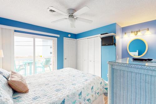 een slaapkamer met een bed en een plafondventilator bij Cozy Carolina Beach Condo in Carolina Beach