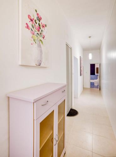 a white kitchen with a vase of flowers on the wall at Cozy Room St Julian's in Il-Gżira