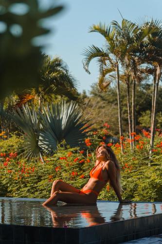 a woman in a orange bikini sitting in a pool at Villa Praia - La Villa Group in Jericoacoara