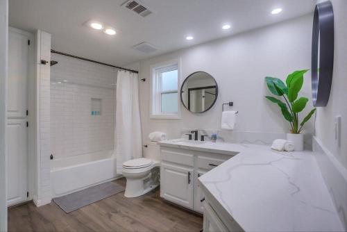 a white bathroom with a sink and a toilet and a mirror at Rip Tide in San Diego