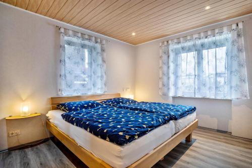 a bedroom with a bed with blue sheets and two windows at Haus Monterosa in Baden-Baden