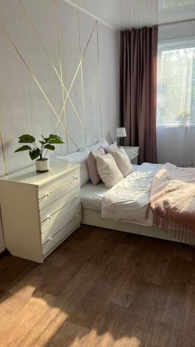 a bedroom with a bed with a dresser and a plant at Уютная двушка в центре in Temirtaū