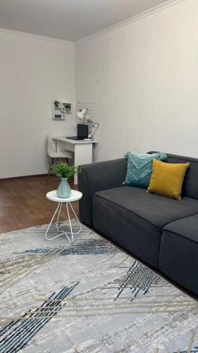 a living room with a blue couch and a table at Уютная двушка в центре in Temirtaū