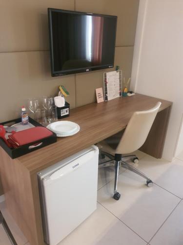 a desk with a tv on top of it at Flip House Jardins in Belo Horizonte