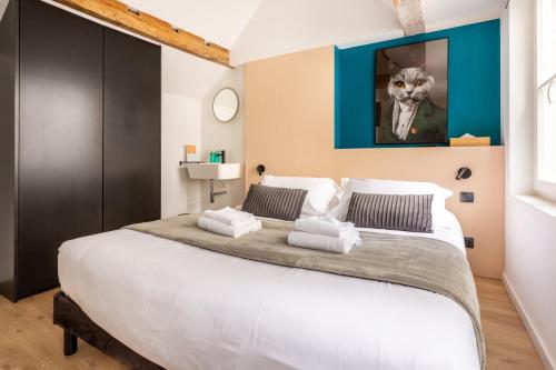 - une chambre dotée d'un grand lit blanc avec une photo de chat sur le mur dans l'établissement Le Chat Qui Dort - Vieux Lille II, à Lille