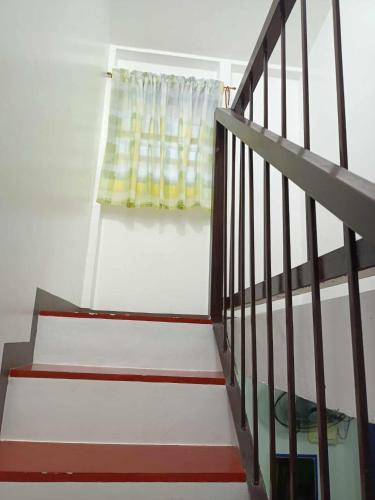 uma escada que leva a uma janela com uma cortina amarela em IRIGA CITY TRANSIENT HOUSE em Iriga City