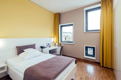 a bedroom with a large bed and two windows at GZT Das Gästehaus in Tübingen