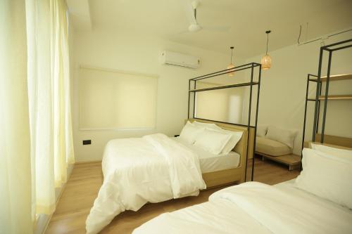 a bedroom with two beds with white sheets and a mirror at The Holiday Home in Srinagar