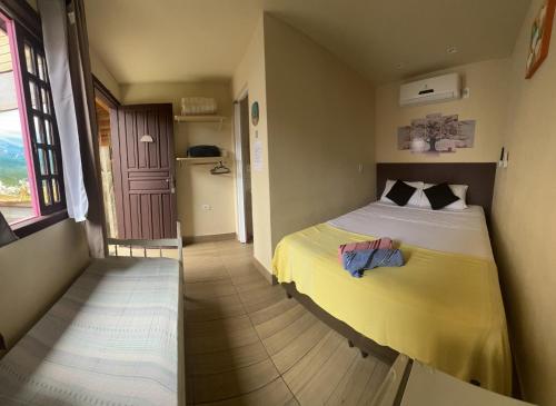 a bedroom with a bed with a yellow blanket at Pousada Voo Livre - Ilha do Mel in Ilha do Mel