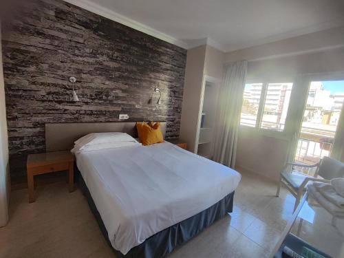 a bedroom with a large bed and a brick wall at Hostal Mar del Plata in El Arenal