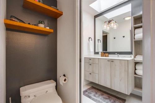 a bathroom with a toilet and a sink and a mirror at Socal Style in Encinitas