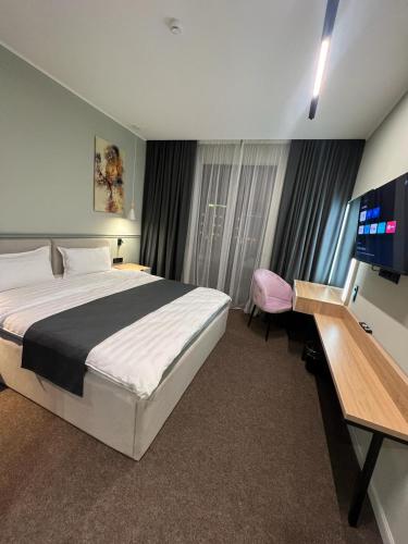 a bedroom with a bed and a desk with a television at Caspian Marine Hotel in Aktau