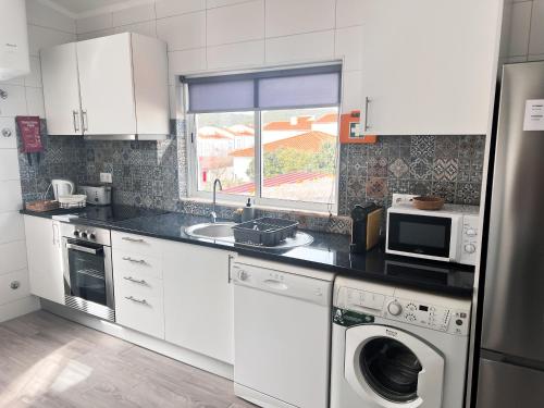 a kitchen with white cabinets and a washer and dryer at Casa Dom Simões in Aljezur