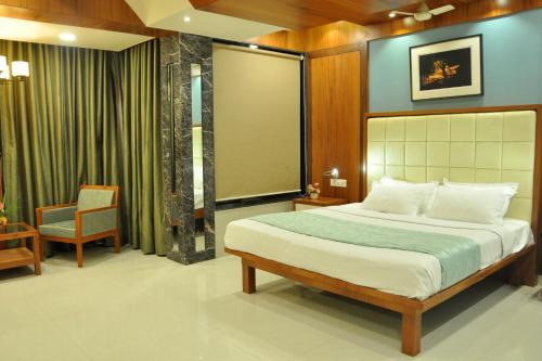 a bedroom with a large bed and a chair at Panaji Residency in Panaji