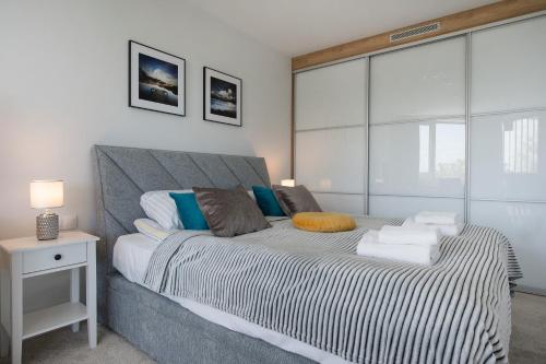 1 dormitorio con 1 cama grande con almohadas azules y blancas en Apartament Premium PINEA 523 en Pobierowo