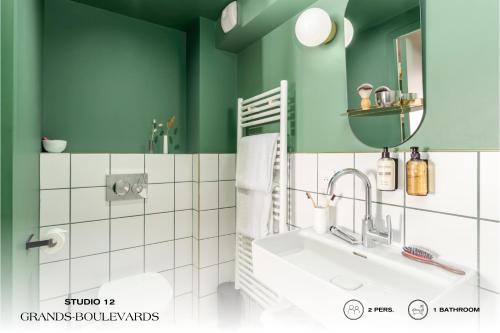 a bathroom with green walls and a sink and a mirror at Beauquartier - Grands Boulevards in Paris