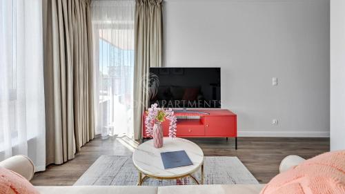 sala de estar con mesa y TV de color rojo en Lion Apartments - SCALA City Center Apartments&Studio IIIC en Gdansk