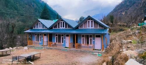 a house with a blue roof on a mountain at MOKSHA COTTAGES AND WOODHOUSE in Kasol
