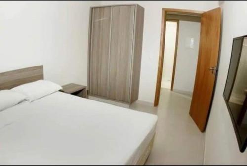 Schlafzimmer mit einem weißen Bett und einem Holzschrank in der Unterkunft Atrium Thermas Residence Service in Caldas Novas