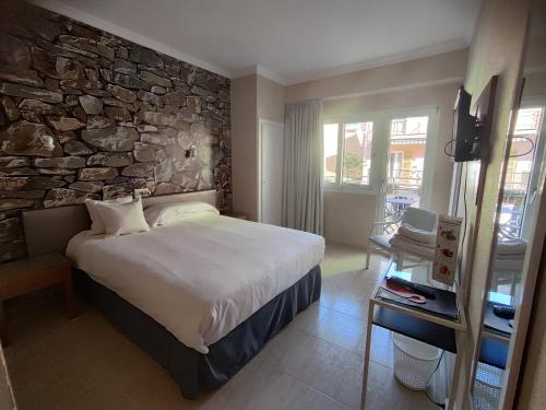 a bedroom with a large bed and a stone wall at Hostal Mar del Plata in El Arenal