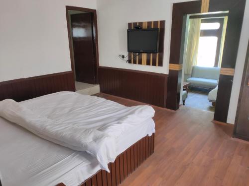 1 dormitorio con 1 cama y TV de pantalla plana en Homeland Cottage, en Manali