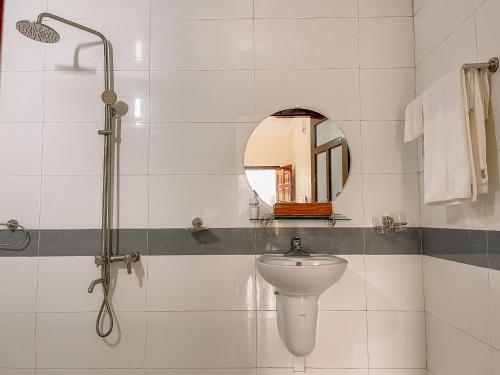 uma casa de banho com um chuveiro, um lavatório e um espelho. em Hải Long em Mộc Châu