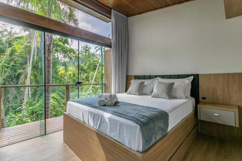 um quarto com uma cama grande e uma janela grande em Recanto Natureza em Florianópolis