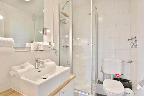 La salle de bains blanche est pourvue d'un lavabo et d'une douche. dans l'établissement Strandschlößchen Strandschlösschen Appartement 5, à Haffkrug