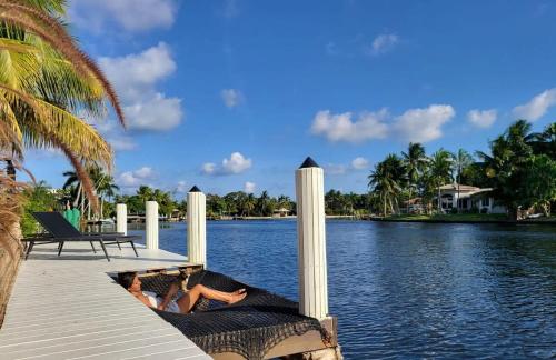two people laying on the end of a dock on the water at VILLA ST-BARTH Waterfront w htd pool by VIAC in Fort Lauderdale