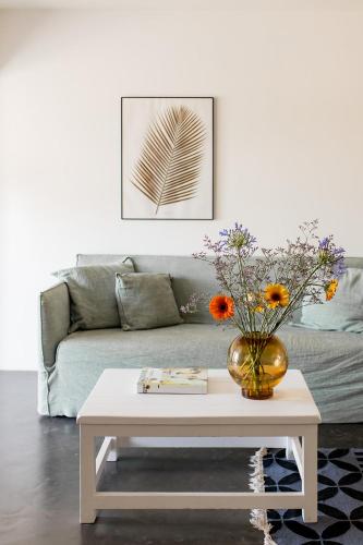 a living room with a couch and a table with flowers at Mas de la Fouque - Hôtel & Spa in Saintes-Maries-de-la-Mer