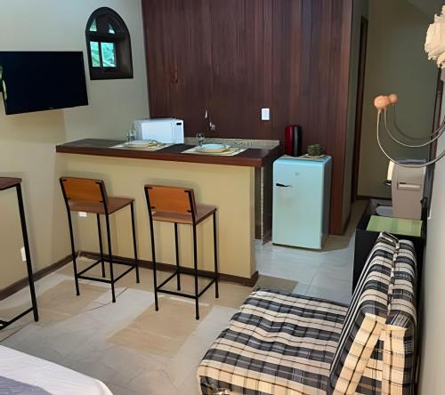 a kitchen with a bar with two chairs and a refrigerator at KORU Cabana - Paz & Romance in Petrópolis