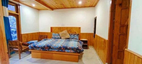 a bedroom with a bed with a blue comforter at MOKSHA COTTAGES AND WOODHOUSE in Kasol